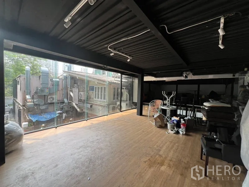 零售空间 出租 - 宽敞零售楼层，黑色外露天花、轨道灯与玻璃立面，面向邻近建筑