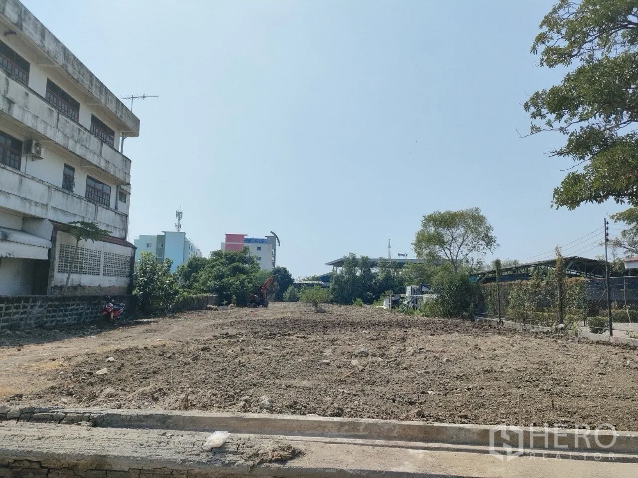 Land for sale in Mueang Samut Prakan, Samut Prakan - Open plot viewed from the frontage, bordered by a wall and fence with neighboring buildings.