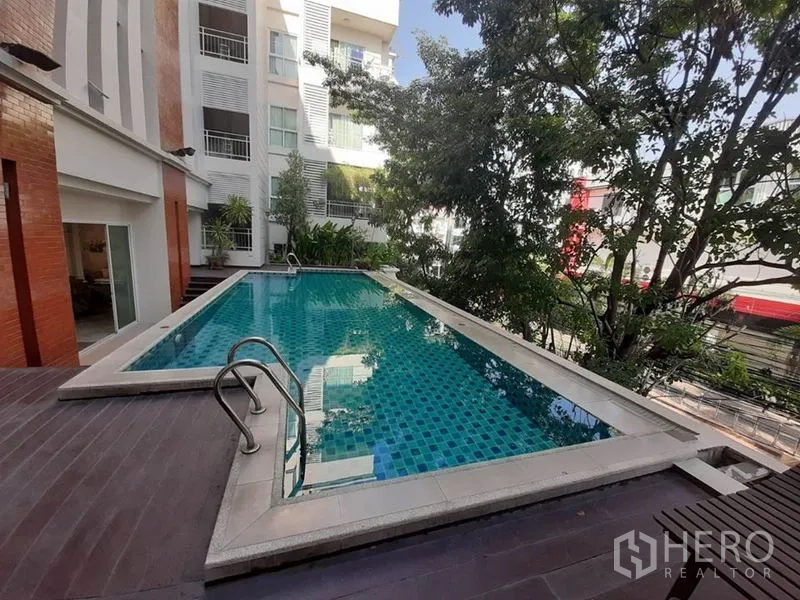 Condominium for sale in Wang Thonglang, Bangkok - Outdoor swimming pool with deck shaded by trees at a low-rise condo.