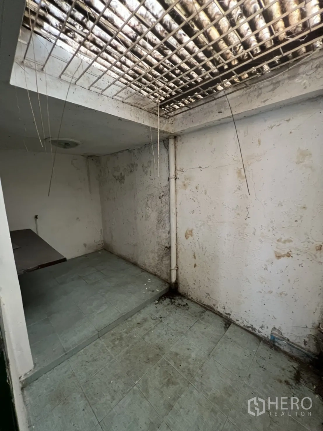 Townhouse for sale in Watthana, Bangkok - Ventilated service zone with skylight grille and weathered walls for renovation.