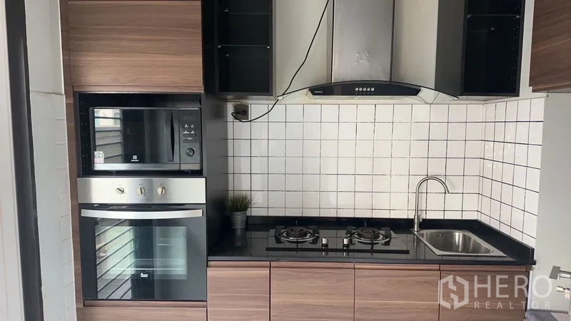 Detached House for rent in Bang Phli, Samut Prakan - Kitchen close‑up showing built‑in oven, microwave, gas burners, hood and sink.