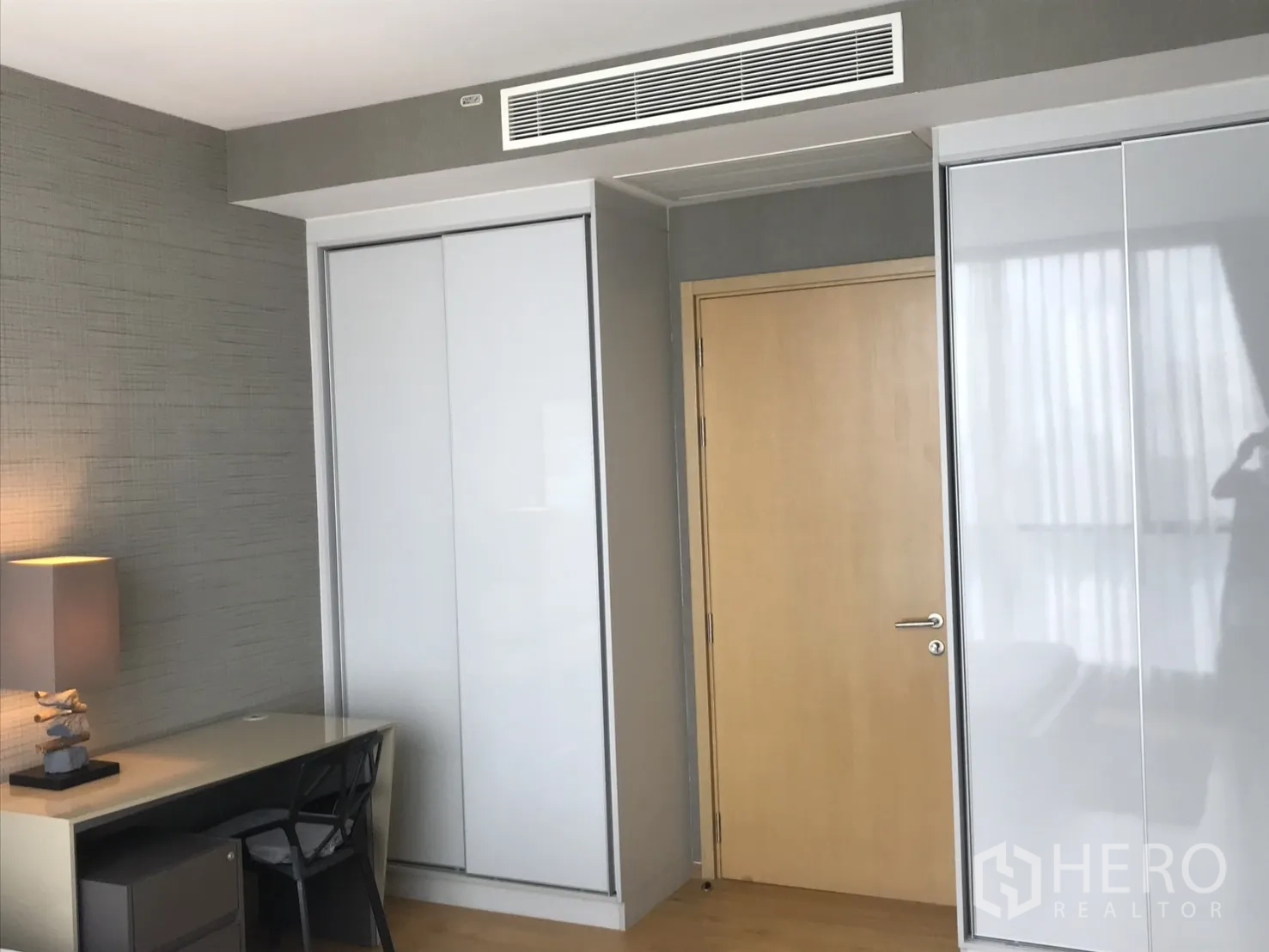 Condominium for rent in Watthana, Bangkok - Primary bedroom showing entrance to the ensuite bathroom and a low TV cabinet.