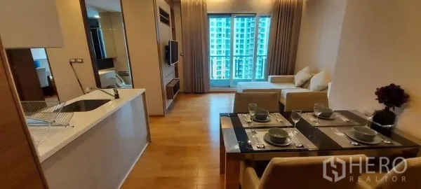 Condominium for rent in Ratchathewi, Bangkok - Modern kitchen connecting to dining and living areas leading to a view balcony.
