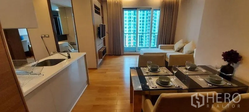 Condominium for rent in Ratchathewi, Bangkok - Modern kitchen connecting to dining and living areas leading to a view balcony.