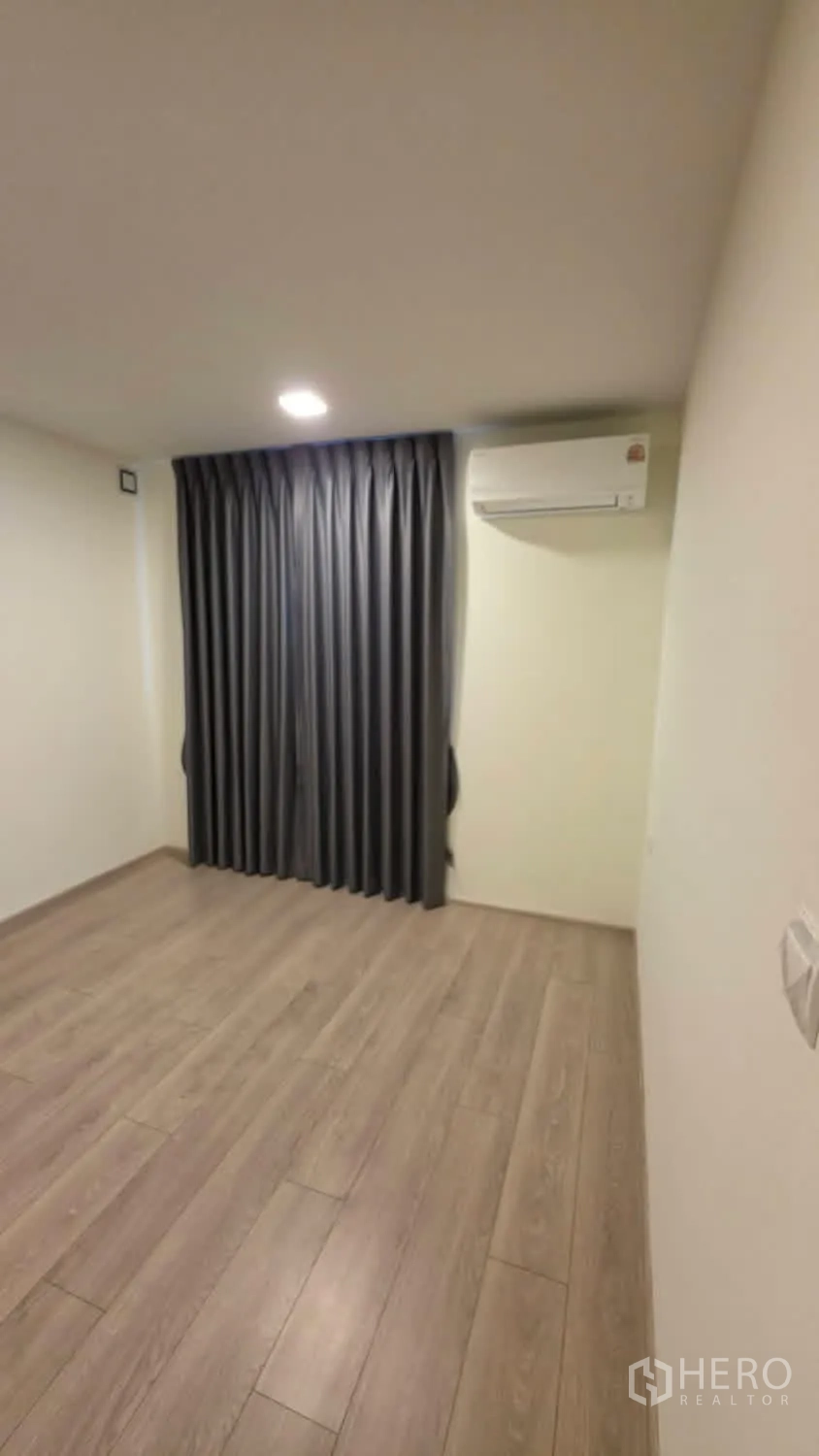 Detached House for rent in Bang Phli, Samut Prakan - Empty room with wood-look flooring, blackout curtains, and an air conditioner.
