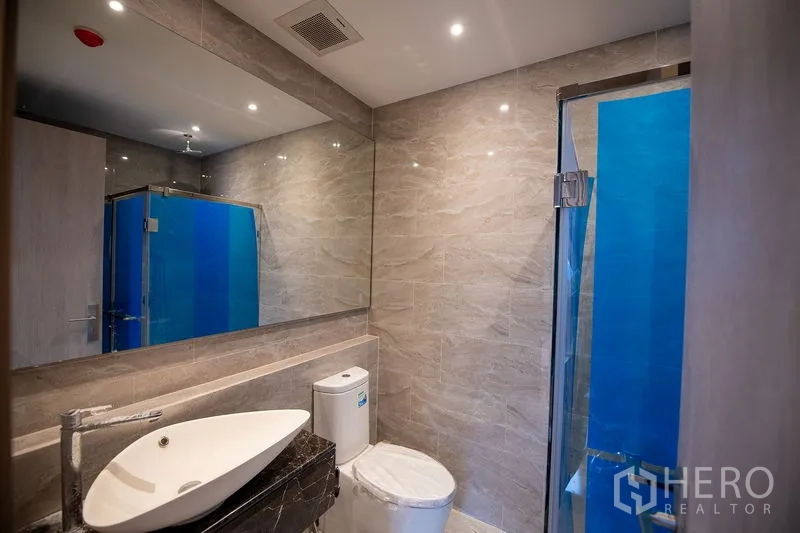 公寓 出租在Din Daeng, Bangkok - 现代浴室，大理石纹瓷砖、台上盆、坐便与玻璃淋浴房。