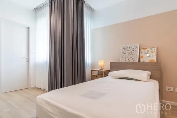 ทาวน์เฮาส์ ให้เช่าหรือขายในSuan Luang, Bangkok - ห้องนอนรอง เตียงเดี่ยว โต๊ะข้าง ผ้าม่านสีเทา และพื้นไม้โทนอ่อน