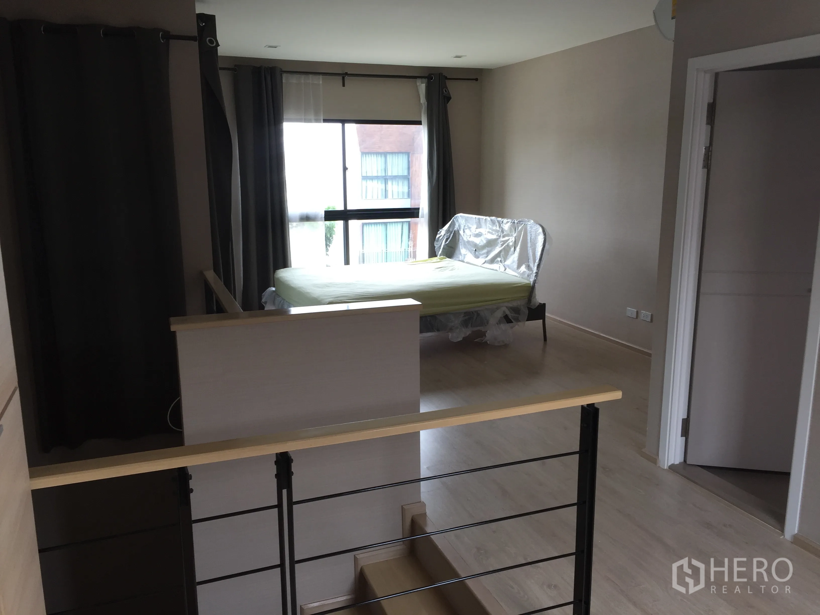 ทาวน์เฮาส์ ให้เช่าในSuan Luang, Bangkok - ห้องนอนมาสเตอร์ หน้าต่างบานใหญ่ เตียง และประตูเข้าสู่ห้องน้ำใกล้โถงบันได