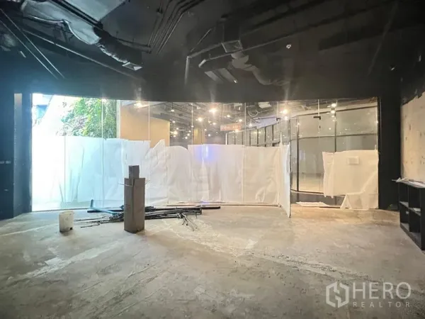 零售空间 出租 - 空置商铺内部，50平米，外露高挑天花与射灯，弧形落地玻璃门面正在准备中。