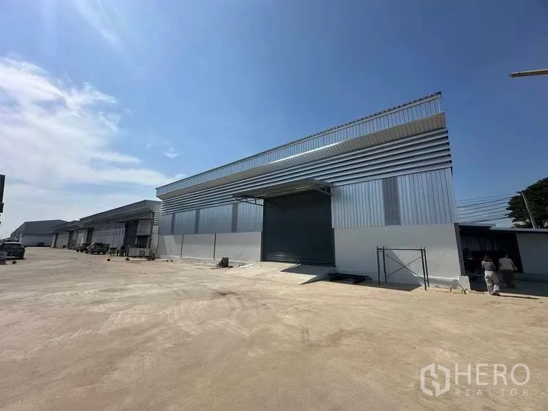 Warehouse for rent in Bang Bua Thong, Nonthaburi - Row of new warehouses with loading bays along a spacious internal road.