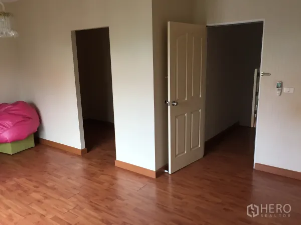 Townhouse for rent or sale in Bueng Kum, Bangkok - Empty room with warm wood floors and two doorways leading to adjoining spaces.