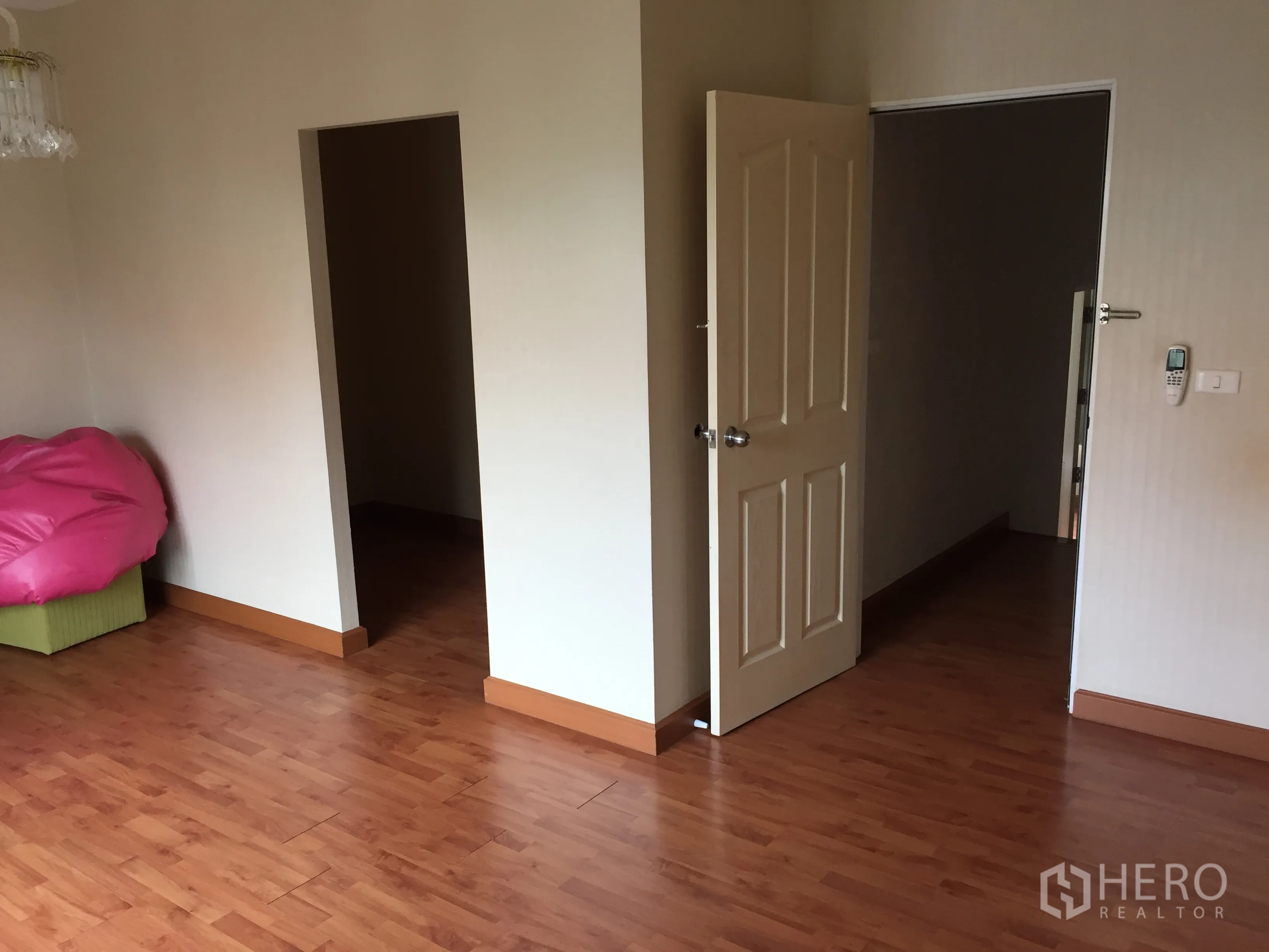 Townhouse for rent or sale in Bueng Kum, Bangkok - Empty room with warm wood floors and two doorways leading to adjoining spaces.