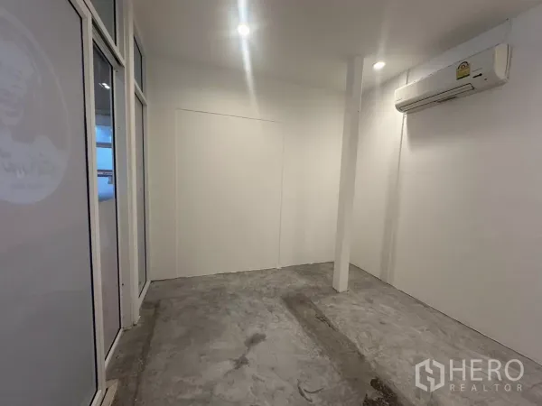 พื้นที่ขายปลีก ให้เช่า - มุมมองไปยังหน้าร้านกระจก พร้อมเสา ไฟฝังฝ้า พื้นคอนกรีต และแอร์ติดผนัง