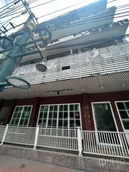 อาคารพาณิชย์ ให้เช่าในWatthana, Bangkok - ด้านหน้าตึกแถวหลายชั้น มีระเบียง กระจกหน้าร้านบานใหญ่ และสายไฟริมถนน