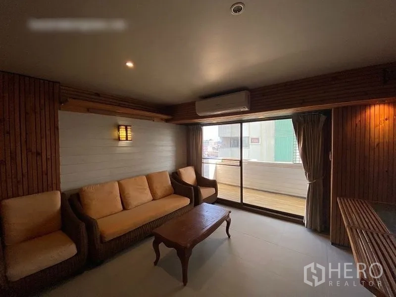 Condominium for rent or sale in Suan Luang, Bangkok - Cozy sitting area with sofa set, air conditioner and sliding doors to a balcony.