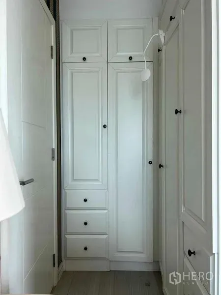 Condominium for sale in Huai Khwang, Bangkok - Built-in white wardrobes and storage in a compact hallway.