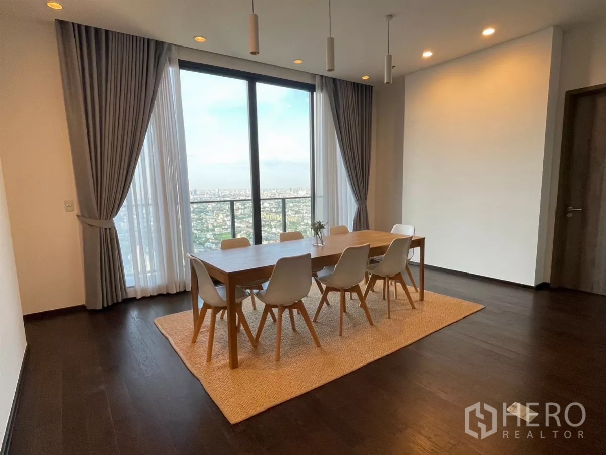 Condominium for rent in Phra Khanong, Bangkok - Dining area with wooden table for six beside large glass doors opening to panoramic views.