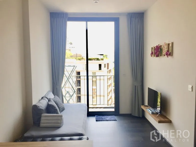 公寓 出租在Watthana, Bangkok - 明亮客厅，沙发、电视层板及通往阳台的推拉落地门。