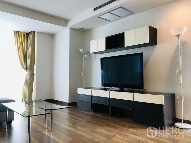 คอนโด ให้เช่าในPathum Wan, Bangkok - ห้องนั่งเล่นสว่าง ทีวีจอใหญ่บนชั้นวางสมัยใหม่ พื้นไม้ และโคมไฟยืน