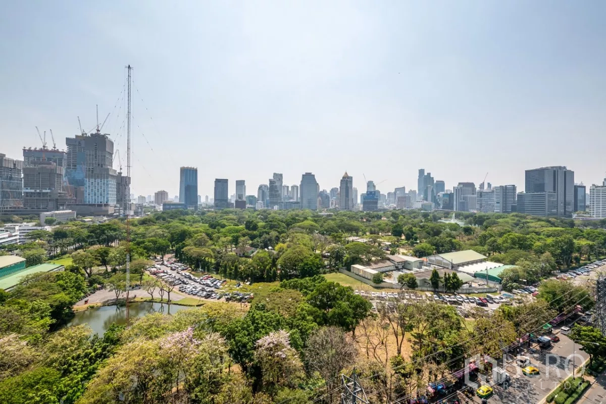 Condominium for rent or sale in Pathum Wan, Bangkok - Panoramic view of Bangkok skyline rising above a vast green city park.