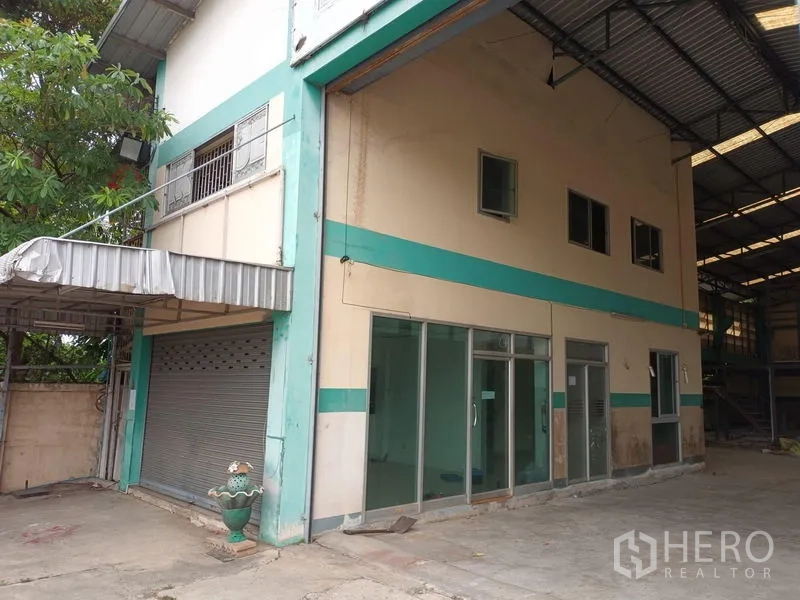 Warehouse for rent in Phasi Charoen, Bangkok - Front office corner with glass doors, shuttered bay and covered awning.