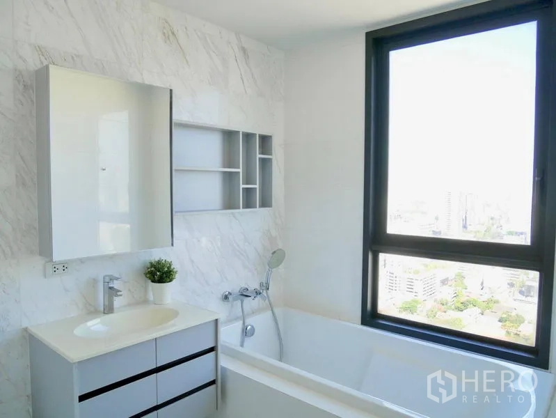 公寓 出租在Watthana, Bangkok - 当代风格浴室，石纹墙面，设浴缸、洗手台与大窗，眺望城市景观。