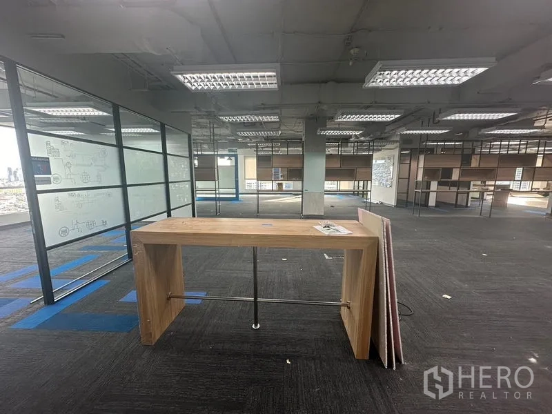 Office Space for rent in Bang Rak, Bangkok - Wooden standing table in a wide office with carpet tiles and urban views.