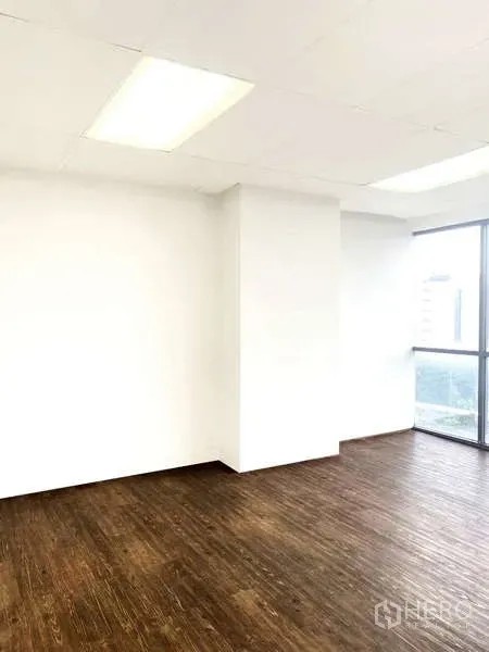 办公空间 出租 - 采光明亮的转角办公区，木地板、白墙与天花灯，旁有高窗。