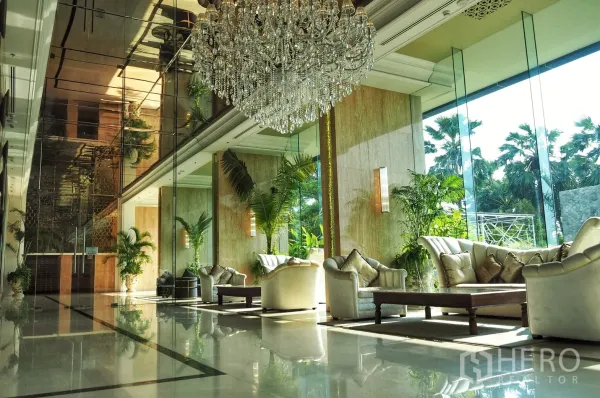 Condominium for rent in Bang Lamung, Chon Buri - Elegant condo lobby featuring a grand crystal chandelier, floor-to-ceiling windows and plush sofas amid greenery.