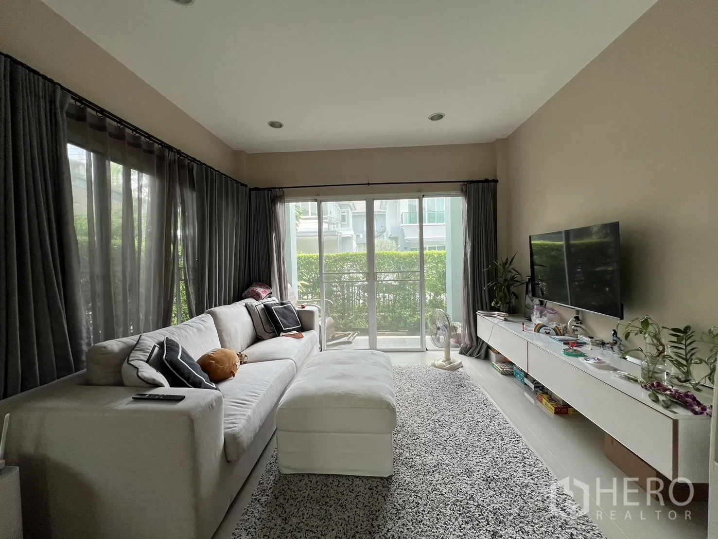 Detached House for rent or sale in Saphan Sung, Bangkok - Bright living room with large sofa, TV wall and floor-to-ceiling glass doors.