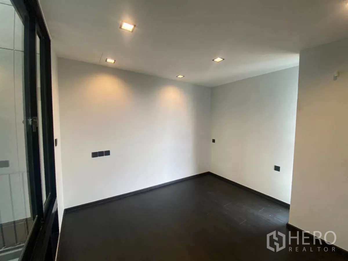 ทาวน์เฮาส์ ให้เช่าในHuai Khwang, Bangkok - ห้องนอนมินิมอล พื้นสีเข้มและหน้าต่างบานเลื่อนขนาดใหญ่.