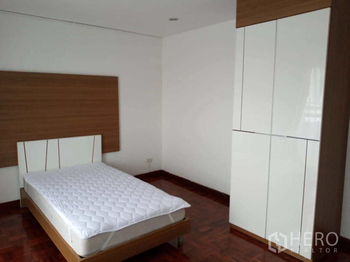 อพาร์ทเมนท์ ให้เช่าในWatthana, Bangkok - ห้องนอนพร้อมเตียงดับเบิล ตู้เสื้อผ้าบานเงาสีขาว และผนังไม้ตกแต่ง