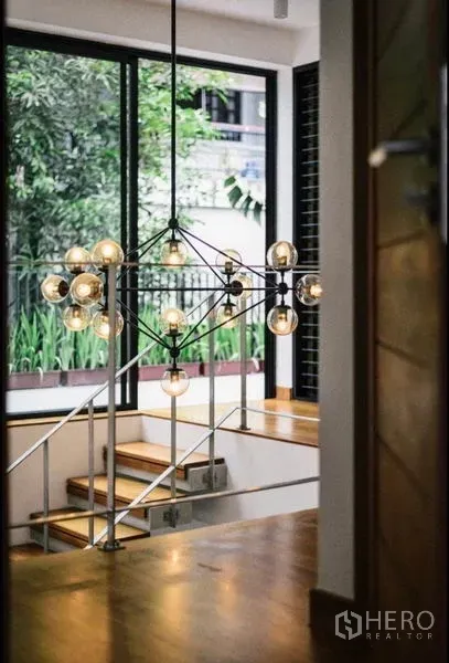 ทาวน์เฮาส์ ให้เช่าในKhlong Toei, Bangkok - โถงบันไดเล่นระดับพร้อมโคมไฟดีไซน์และหน้าต่างบานใหญ่หันสู่สวน
