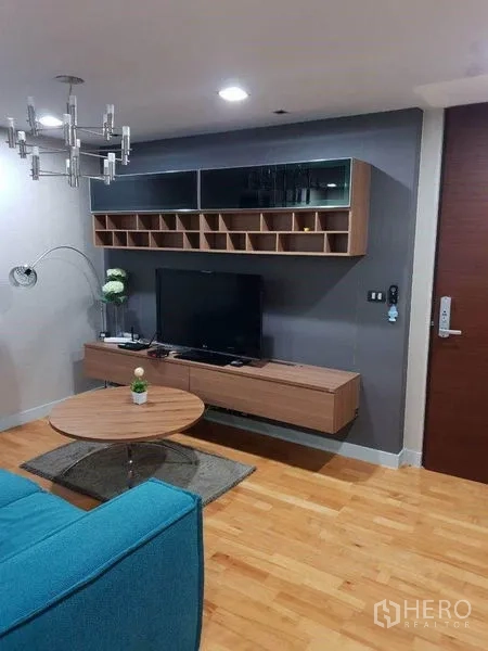 Condominium for sale in Bang Rak, Bangkok - TV console and display shelving in the living area with wood flooring.