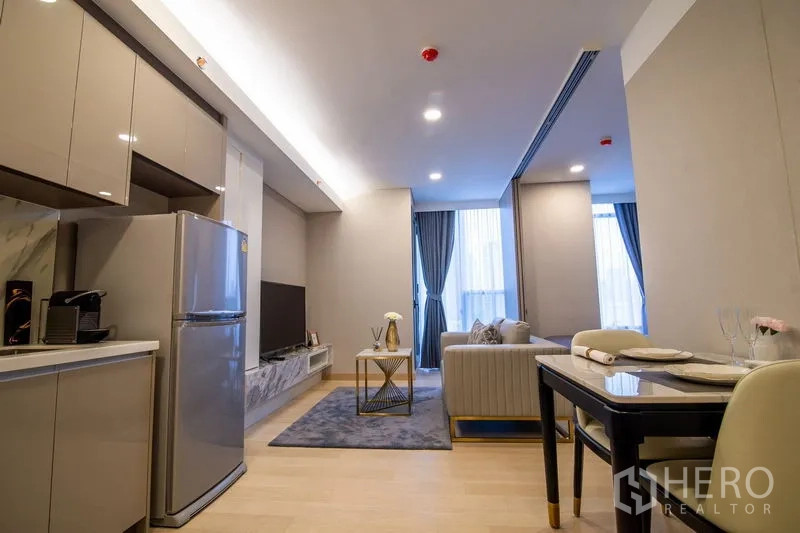 คอนโด ให้เช่าในKhlong Toei, Bangkok - มุมมองจากครัวไปยังห้องนั่งเล่น มีพรม โต๊ะกลาง และประตูระเบียง