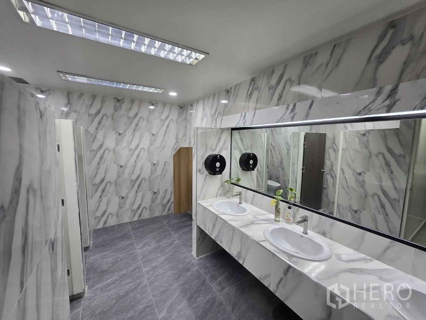 Office Space for rent in Khlong Toei, Bangkok - Modern restroom with marble-effect walls, long mirror, and double sinks.