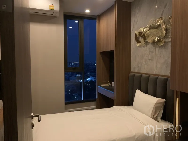 คอนโด ขายในPhra Khanong, Bangkok - ห้องนอนเตียงเดี่ยว ตู้ไม้ และหน้าต่างสูงเห็นวิวเมืองยามค่ำ