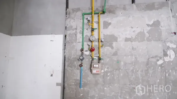 零售空间 出租在Watthana, Bangkok - 近景：已安装的燃气与给水表及彩色管道在未完工墙面上。