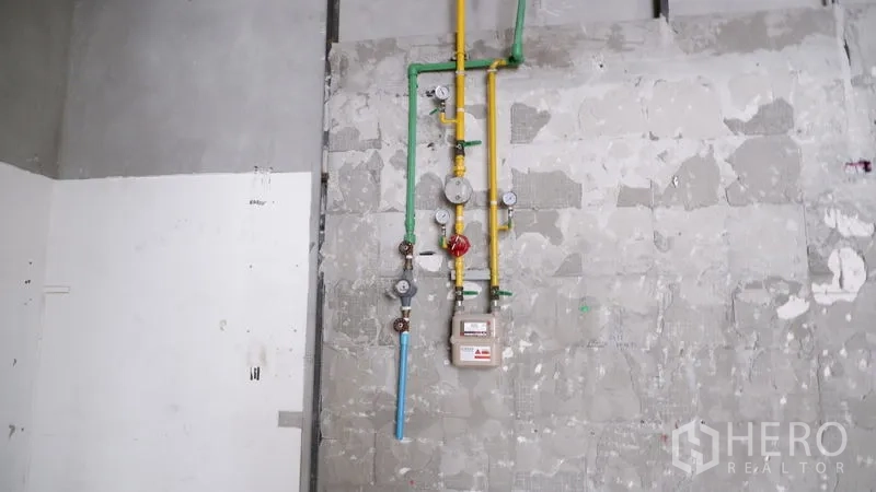 零售空间 出租在Watthana, Bangkok - 近景：已安装的燃气与给水表及彩色管道在未完工墙面上。