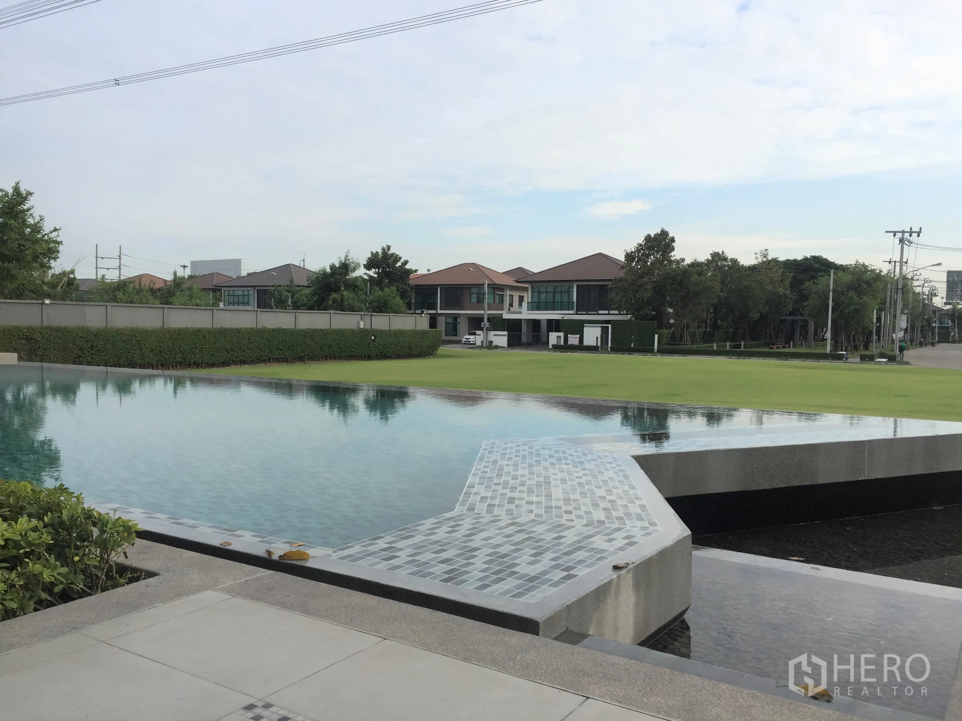 Detached House for rent or sale in Prawet, Bangkok - Resident facilities include a resort-style swimming pool beside an expansive lawn.