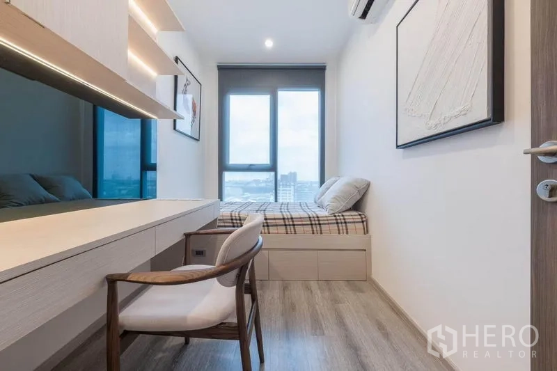 Condominium for rent in Bang Na, Bangkok - Work-and-sleep room featuring a desk with LED lighting and a platform bed near the window.