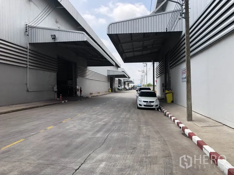 工厂 出租在Wang Noi, Phra Nakhon Si Ayutthaya - 园区宽阔通道，两侧为仓库与外挑雨棚，道路旁停放车辆。