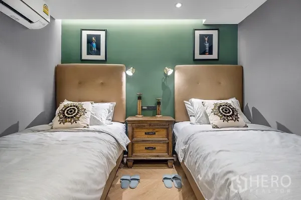 公寓 出租在Bang Rak, Bangkok - 次卧设两张单人床，绿色重点墙与床头柜阅读灯。