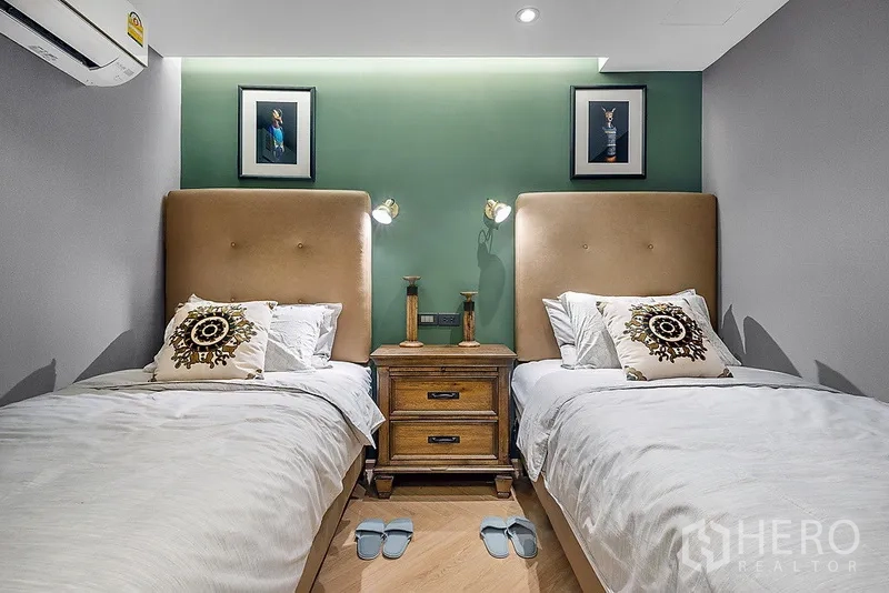 公寓 出租在Bang Rak, Bangkok - 次卧设两张单人床，绿色重点墙与床头柜阅读灯。