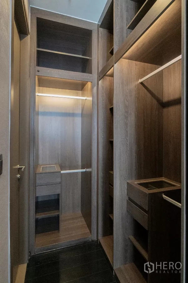 公寓 出租在Watthana, Bangkok - 步入式衣帽间，深色木作柜体与开放格架。