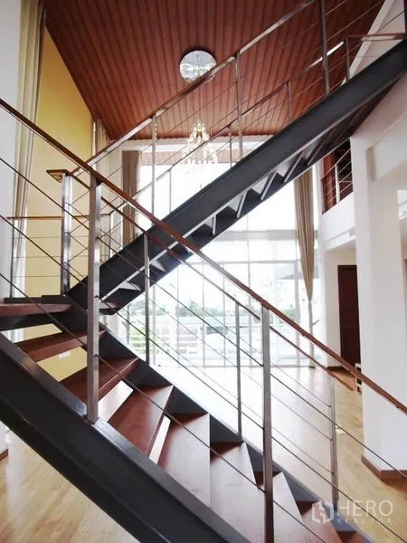 公寓 出租在Chatuchak, Bangkok - 现代钢木楼梯，置于挑高空间与大面积采光窗前。