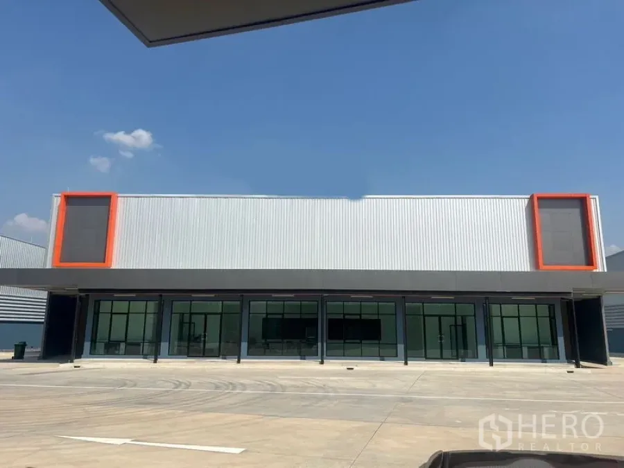 Warehouse for rent in Bang Phli, Samut Prakan - Modern warehouse facade with glass-front offices and orange accents under clear sky