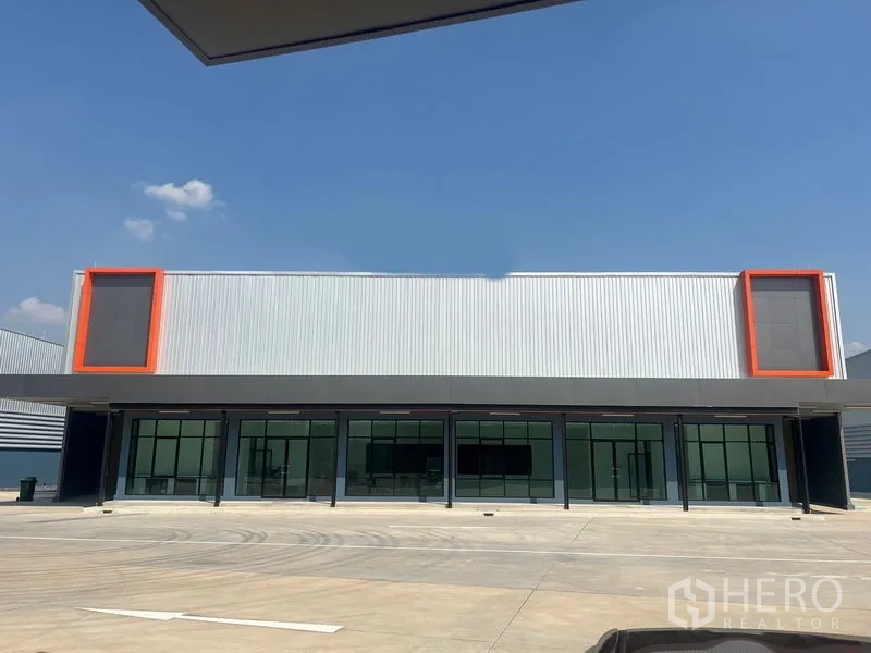 Warehouse for rent in Bang Phli, Samut Prakan - Modern warehouse facade with glass-front offices and orange accents under clear sky