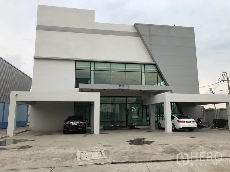 Warehouse for rent in Samut Prakan - Modern glass-front office building at the entrance of the warehouse complex.