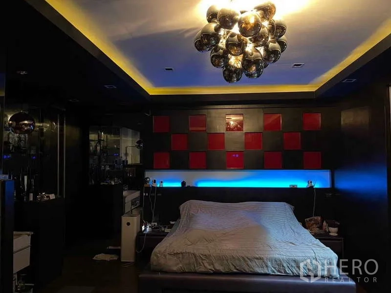 Detached House for sale in Suan Luang, Bangkok - Moody bedroom with modern chandelier, accent lighting and red-and-black headboard wall.